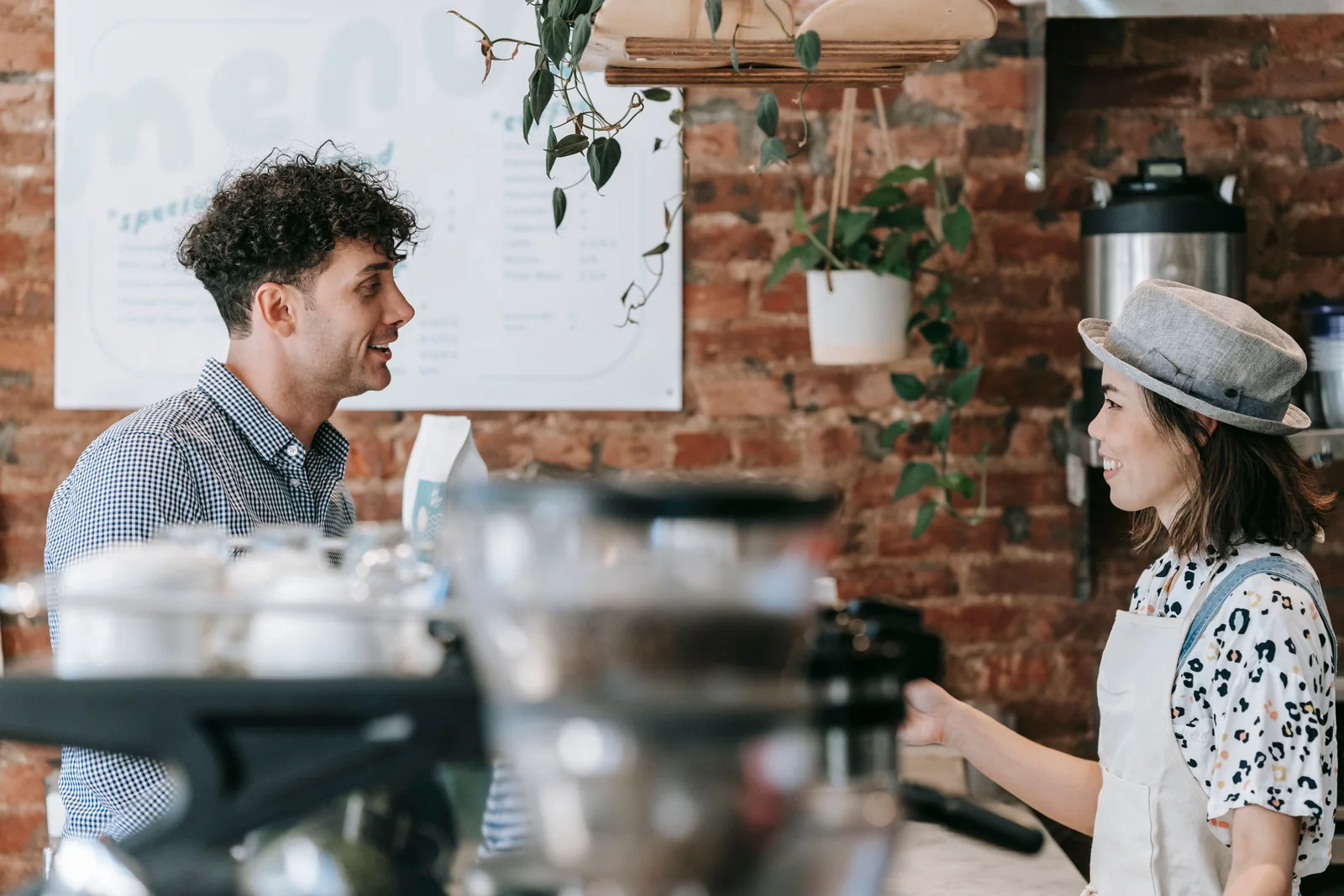 Un barista sorride a una cliente dall’altro lato del bancone del caffè.