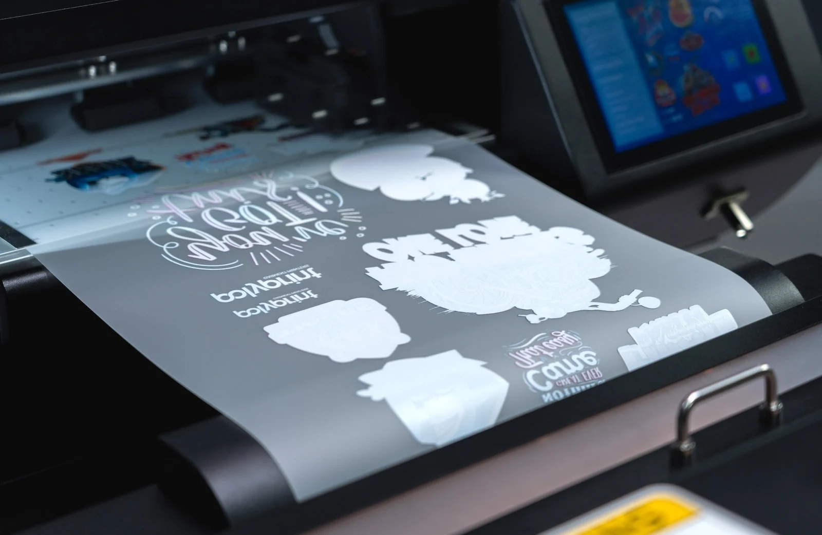 Film transfer con grafiche e strato di inchiostro bianco in uscita da una stampante DTF Polyprint.