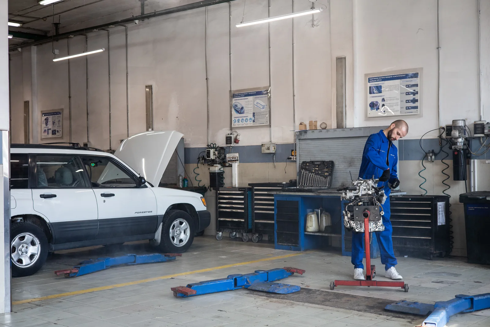 Meccanico in tuta blu al lavoro su un motore in officina.